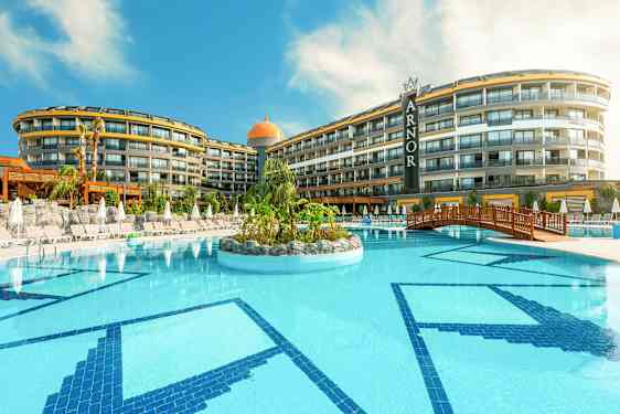 Et hotel med en stor udendørs pool, omgivet af liggestole og parasoller. (AI-genereret tekst)