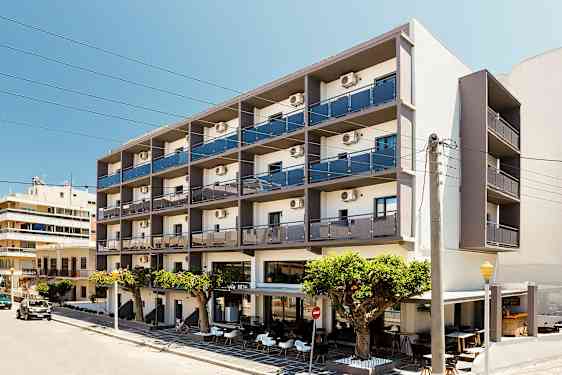 Et fleretagers hotel med altaner og udendørs servering foran, beliggende ved en gade. (AI-genereret tekst)