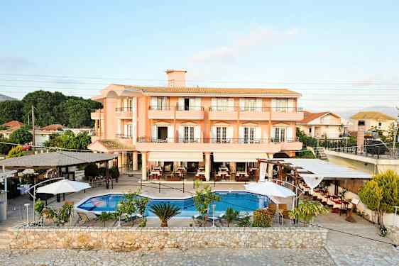 Et hotel med ferskenfarvede facader og en udendørs pool med omkringliggende siddepladser. (AI-genereret tekst)