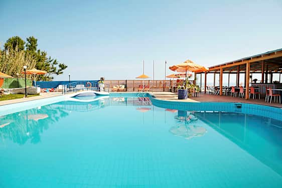 En udendørs pool med parasoller og borde ved siden af. (AI-genereret tekst)