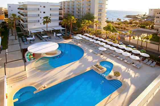 Hotelområde nær havet med pool, liggestole og parasoller. (AI-genereret tekst)