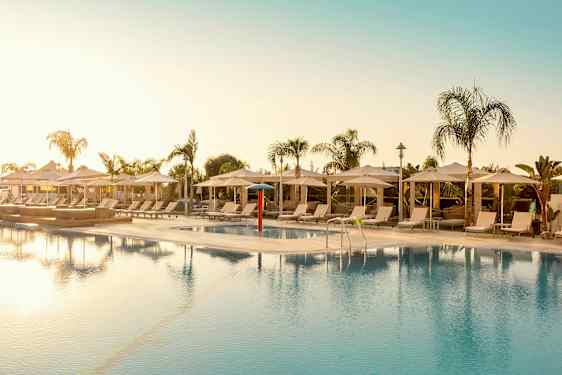 Udendørs pool omgivet af liggestole og parasoller. (AI-genereret tekst)