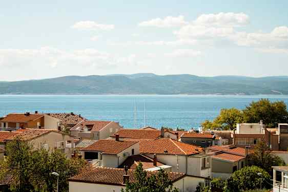 Røde tagene på huse med havet og bakker i baggrunden. (AI-genereret tekst)