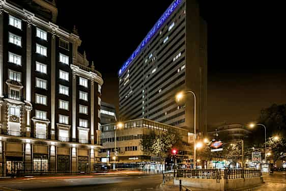 En byvej om natten med oplyste bygninger og lysskilte. (AI-genereret tekst)