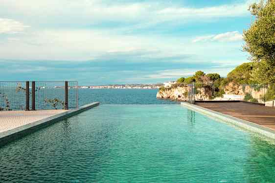 En infinitypool med udsigt over havet og klipper i baggrunden. (AI-genereret tekst)