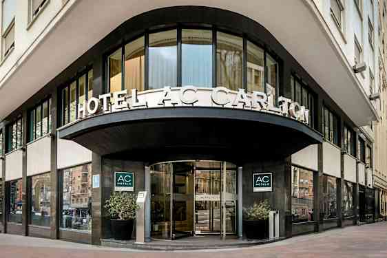 En hotelfacade med skilteteksten "HOTEL AC CARLTON" synlig over indgangen. (AI-genereret tekst)