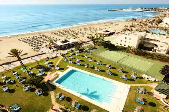 Hotellets poolområde med udsigt over stranden og havet. (AI-genereret tekst)