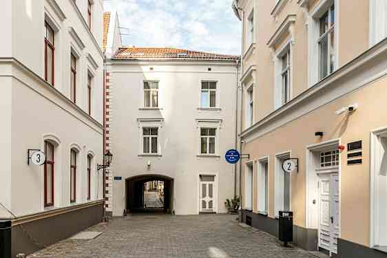 En smal gade omgivet af lyse bygninger med vinduer og døre. (AI-genereret tekst)