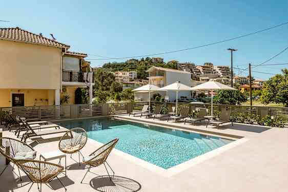 Udendørs pool med solsenge og parasoller i et boligområde. (AI-genereret tekst)