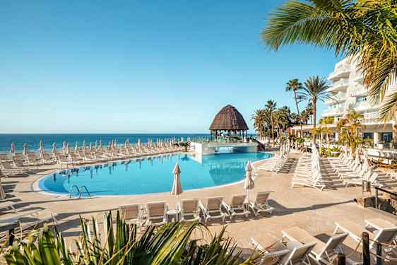 Poolområde med liggestole og parasoller nær havet. (AI-genereret tekst)