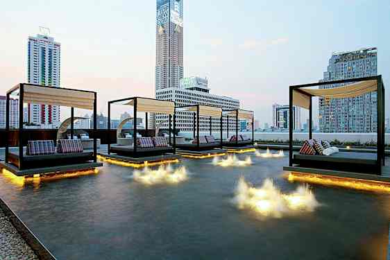 Billede af en moderne byudsigt med dagsenge placeret over en lav pool med lysinstallationer i vandet. (AI-genereret tekst)