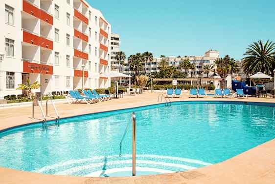 En udendørs pool med liggestole ved et hotel. (AI-genereret tekst)