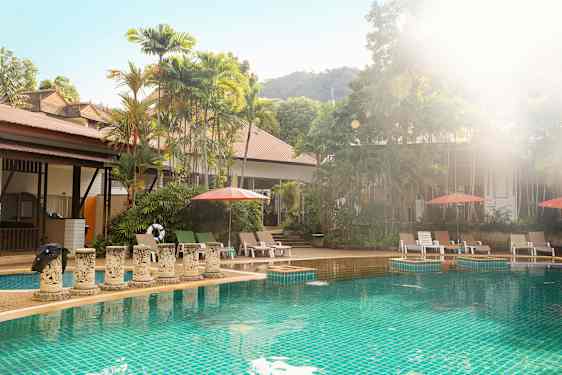 Udendørs pool med liggestole og parasoller, omgivet af frodige træer. (AI-genereret tekst)