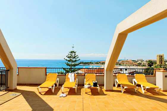 Terrasse med liggestole og havudsigt. (AI-genereret tekst)