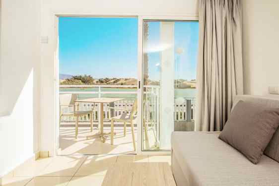 Udsigt fra en stue mod balkonen og landskabet i baggrunden. (AI-genereret tekst)