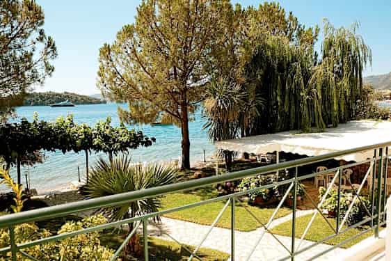 Udsigt over en have med frodige planter, træer og havet i baggrunden. (AI-genereret tekst)