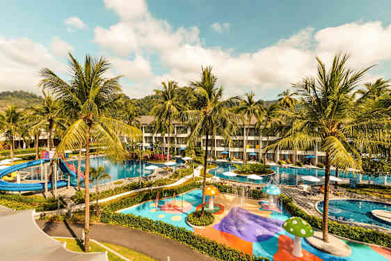 Billede af et hotelområde med swimmingpools, vandrutsjebane og farverige legeområder omgivet af palmer. (AI-genereret tekst)