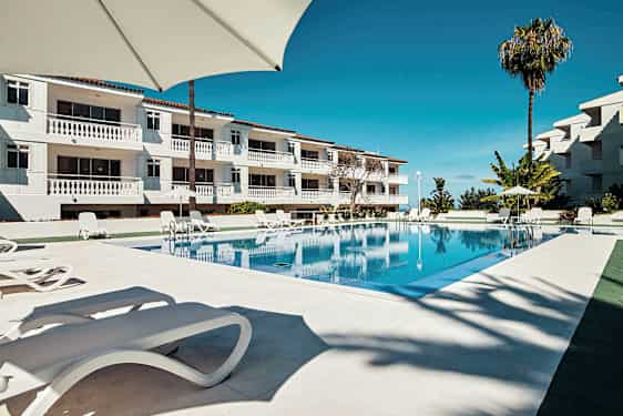 En pool ved et hotel med liggestole og parasoller. (AI-genereret tekst)