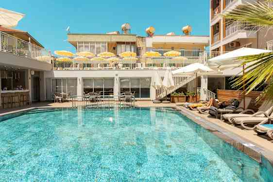 En udendørs pool omgivet af liggestole og parasoller på et hotel. (AI-genereret tekst)