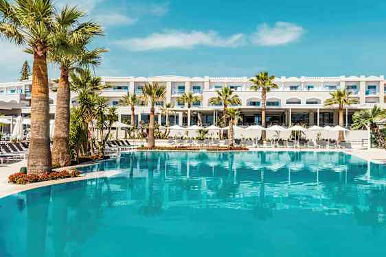 Hotelbygning bag en stor pool med palmer. (AI-genereret tekst)