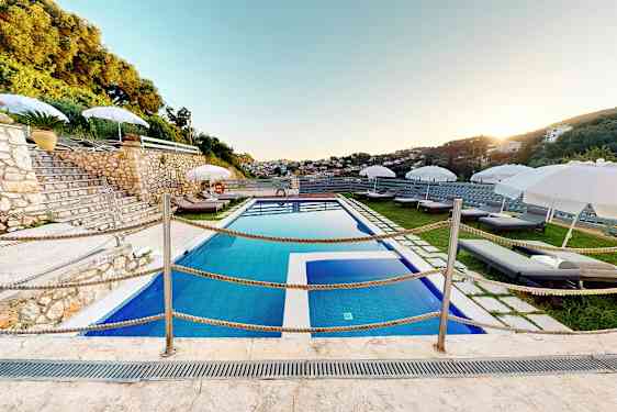 Udendørs pool med liggestole og parasoller på en terrasse. (AI-genereret tekst)