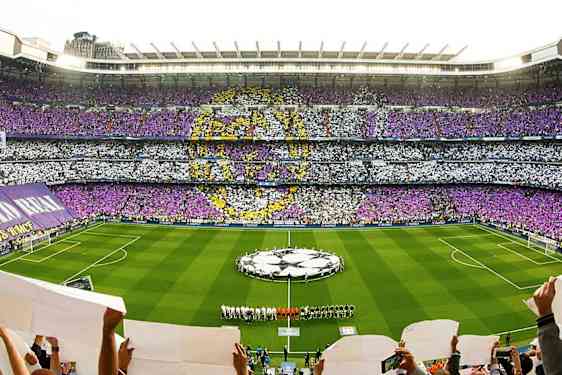 Et fyldt fodboldstadion med farvet publikumsmønster og hold på banen. (AI-genereret tekst)