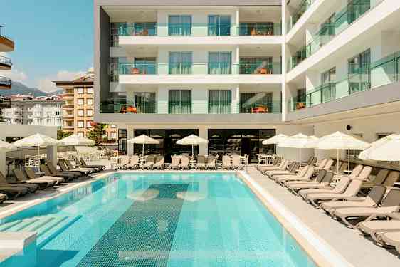 Poolområde med liggestole og parasoller foran et hotel. (AI-genereret tekst)