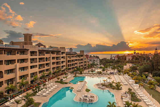 Udsigt over et hotel med poolområde ved solnedgang. (AI-genereret tekst)