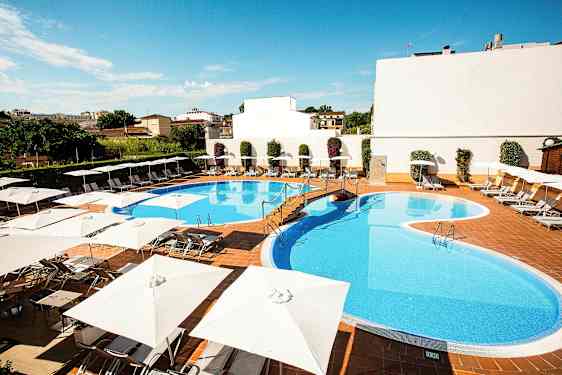 En udendørs pool omgivet af liggestole og parasoller. (AI-genereret tekst)