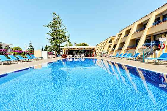 Et hotelområde med en pool i forgrunden, liggestole på begge sider og en bar i baggrunden. (AI-genereret tekst)