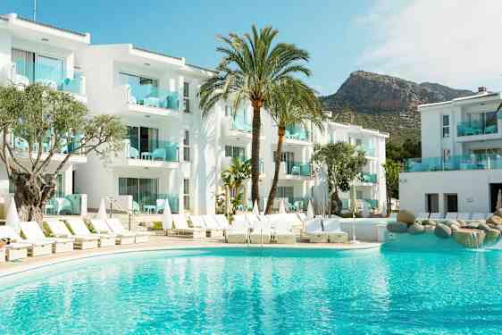 Billede af et hotel med hvide bygninger, en pool og liggestole, omgivet af palmer. (AI-genereret tekst)