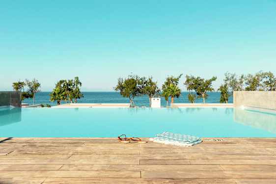 Billede af en infinitypool med udsigt over havet og træer i baggrunden. (AI-genereret tekst)