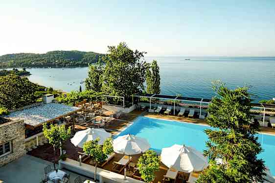 Swimmingpool med parasoller og udsigt over havet. (AI-genereret tekst)