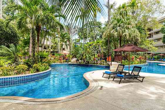 Billede af en udendørs pool omgivet af tropiske planter og liggestole. (AI-genereret tekst)