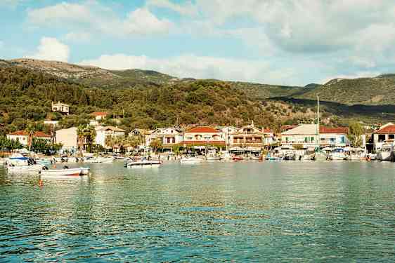 En havbugt med småbåde og en kystby fyldt med huse og træer i baggrunden. (AI-genereret tekst)