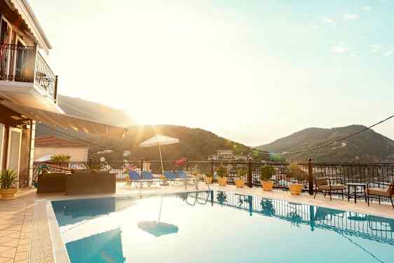 Udendørs pool med liggestole og parasol, omgivet af frodige bjerge. (AI-genereret tekst)