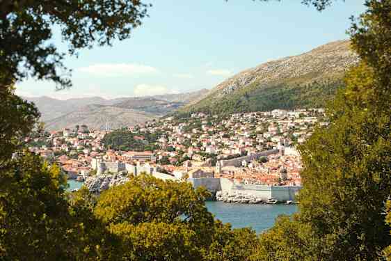 En udsigt over Dubrovnik med dens historiske bymur, omgivet af grønne områder. (AI-genereret tekst)