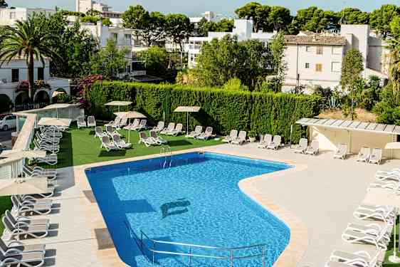 Udendørs pool med liggestole og parasoller ved siden, omgivet af grønne områder og bygninger. (AI-genereret tekst)