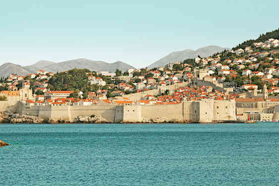 Stenbyers mure og røde tage ved kysten. (AI-genereret tekst)