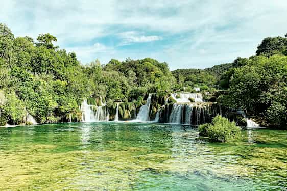 Et naturskønt vandfald omgivet af frodig vegetation. (AI-genereret tekst)