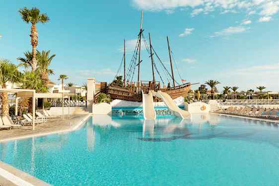 Udendørs pool med rutsjebaner fra et piratskib og omkringliggende liggestole. (AI-genereret tekst)