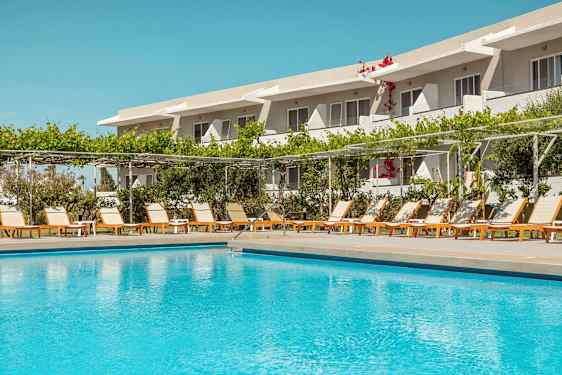 Udendørs pool foran en række liggestole og et hotel i baggrunden. (AI-genereret tekst)