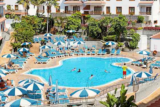 Udendørspool med liggestole, parasoller og mennesker, der svømmer. (AI-genereret tekst)