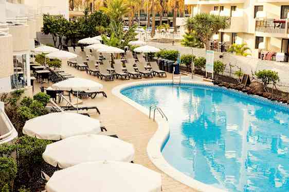 Poolområde med liggestole og parasoller ved et hotel. (AI-genereret tekst)