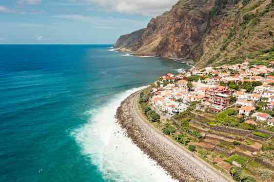 Udsigt over en kystlinje med en landsby på klippen og havet i baggrunden. (AI-genereret tekst)