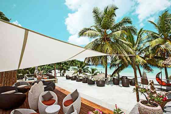 Udendørsområde med siddepladser og palmer ved en strand. (AI-genereret tekst)