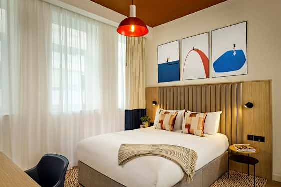 Et stilfuldt hotelværelse med en stor seng og moderne kunstværker på væggen. (AI-genereret tekst)