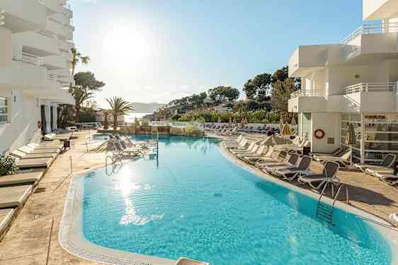 Udendørs pool med liggestole omkring, ved et hotel i solrigt vejr. (AI-genereret tekst)