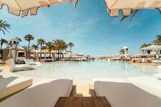 En luksuriøs pool omgivet af solsenge og parasoller i en sommerlig atmosfære. (AI-genereret tekst)