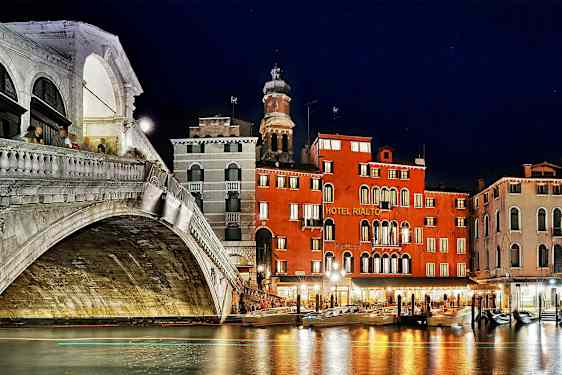 En natudsigt af Rialto-broen og nærliggende bygninger ved Grand Canal i Venedig. (AI-genereret tekst)